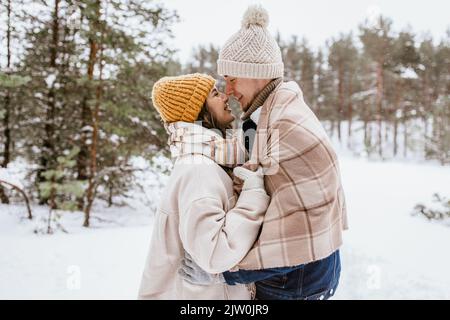 un couple souriant se touche le nez en hiver Banque D'Images
