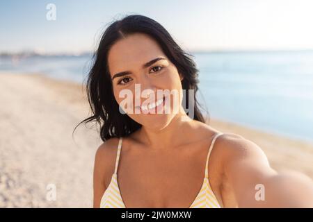 femme souriante en bikini prenant selfie sur la plage Banque D'Images