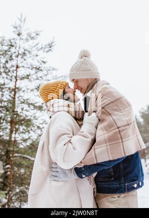 un couple souriant se touche le nez en hiver Banque D'Images