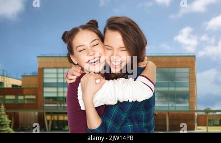 des adolescentes joyeuses qui s'embrasent sur le fond de l'école Banque D'Images