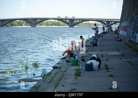 Pêcheurs sur la rive de la rivière Dniepr (Dnipro) à Kiev avec la vue sur l'île et le pont du métro, guérir le stress, célébrer le jour de l'indépendance. Banque D'Images