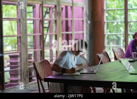 Jeune femme ou étudiant ciblé prenant des notes, utilisant un ordinateur portable, apprenant des langues étrangères Banque D'Images
