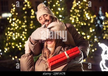 couple heureux avec cadeau sur les lumières de noël Banque D'Images
