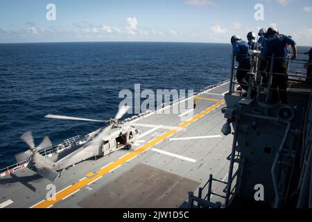 MER DE CHINE ORIENTALE (AOÛT 31, 2022) des marins, affectés au porte-avions amphibie déployé à l’avant USS America (LHA 6), observent un hélicoptère MH-60s Sea Hawk, du détachement 6 de l’Escadron de combat de la mer (HSC) 25, lors d’opérations de vol sur le pont de vol du navire en naviguant en mer de Chine orientale, le 31 août 2022. L'Amérique, navire chef de file du America Amphiobie Ready Group, opère dans la zone d'opérations 7th de la flotte pour améliorer l'interopérabilité avec ses alliés et ses partenaires et servir de force de réaction prête à l'emploi pour défendre la paix et la stabilité dans la région Indo-Pacifique. (É.-U. Bleu marine photo par Mas Banque D'Images