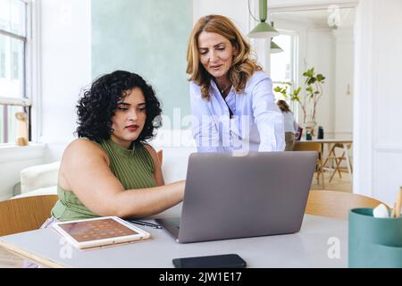 Des femmes d'affaires multiraciales discutent de stratégie d'entreprise au lieu d'un ordinateur portable lors d'une réunion au bureau Banque D'Images