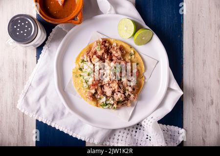 Taco de Carnitas. Tortilla au cornmeal avec porc frite. Apéritif mexicain traditionnel généralement accompagné de coriandre, d'oignon et de sauce chaude. Banque D'Images