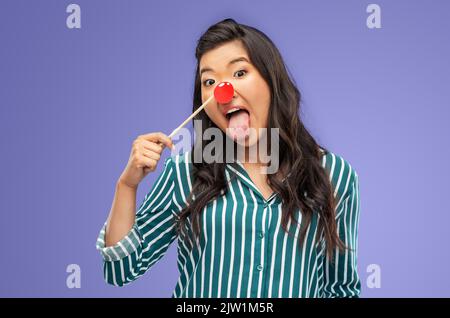 drôle de femme avec le nez clown rouge montrant la langue Banque D'Images