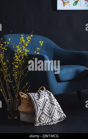 chaise, couverture dans le panier et branches dans la pièce sombre Banque D'Images