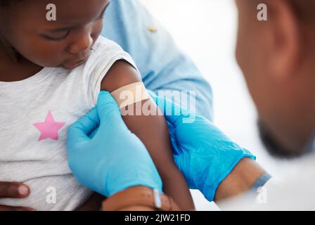 Médecin, travailleur de la santé et professionnel de la santé avec du plâtre sur le bras de l'enfant malade après le vaccin Covid, faisant le contrôle après la blessure et de protéger de Banque D'Images