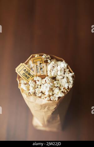 Les films sont identiques sans pop-corn. Un sac de pop-corn et deux billets de cinéma sur fond de bois. Banque D'Images