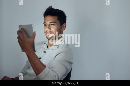Quelle est la dernière nouveauté sur les réseaux sociaux : un jeune homme qui utilise sa tablette la nuit. Banque D'Images