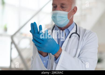 Un médecin de sexe masculin âgé de race blanche portant un masque facial et des gants de protection Banque D'Images