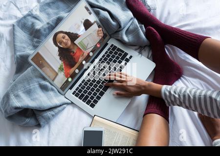 Femme d'affaires biraciale présentant un rapport à une jeune femme indépendante travaillant à domicile via un ordinateur portable Banque D'Images