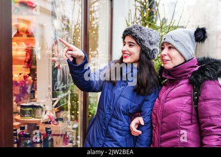 Les femmes gaies regardant le magasin de fenêtre de magasin. Des acheteurs curieux heureux Banque D'Images