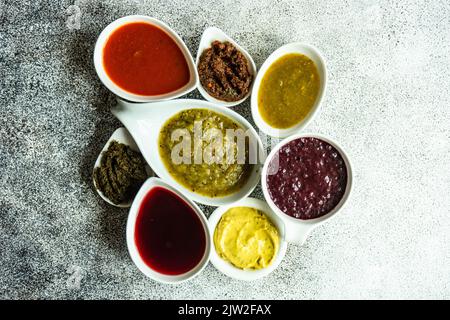 Concept de cuisine géorgienne traditionnelle avec une variété d'épices, de sauces et d'herbes dans des bols en céramique sur fond de béton gris Banque D'Images