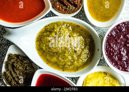 Concept de cuisine géorgienne traditionnelle avec une variété d'épices, de sauces et d'herbes dans des bols en céramique sur fond de béton gris Banque D'Images