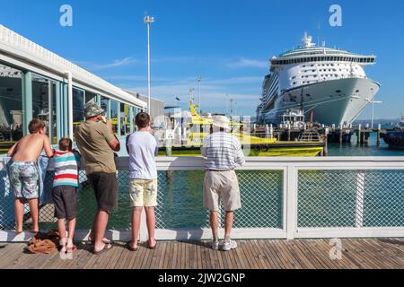 Les gens sur un quai regardant le bateau de croisière 'Voyager des Mers', ancré dans le port de Tauranga, Nouvelle-Zélande Banque D'Images