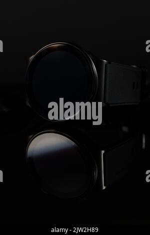 Gros plan sur la mise au point douce d'une montre intelligente moderne avec écran noir rond placé sur une surface sombre Banque D'Images