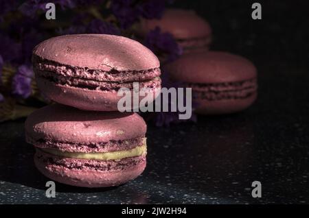 Gros plan de délicieux macarons doux de couleur pourpre empilés sur une table ensoleillée le matin Banque D'Images