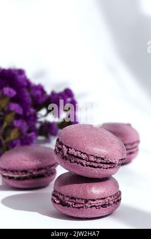 Paire de délicieux macarons doux de couleur pourpre empilés sur une table ensoleillée le matin Banque D'Images