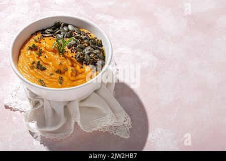 Au-dessus de l'appétissant purée de citrouille saine avec des graines et assaisonnement servi dans un bol en céramique blanche sur la table à la lumière du jour Banque D'Images