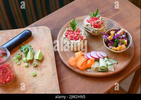 De dessus bol avec salade fraîche sur assiette en bois avec légumes coupés et sandwichs avec pâtés de champignons préparés pour le déjeuner végétarien Banque D'Images