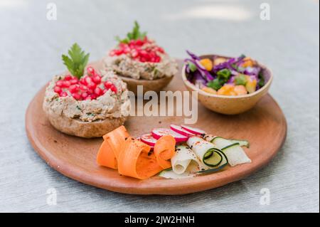 Bol avec salade fraîche sur assiette en bois avec légumes coupés et sandwichs avec pate de champignons préparés pour le déjeuner végétarien Banque D'Images