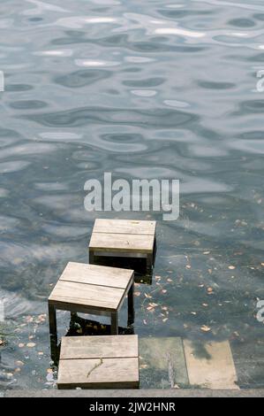 Depuis le dessus des tabourets en bois dans l'eau ondulée du lac de Constance avec des feuilles d'automne tombées le jour ensoleillé Banque D'Images