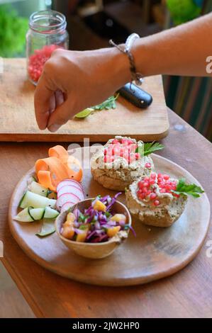 Grand angle de récolte cuire sans visage saupoudrer la salade de légumes frais avec l'assaisonnement tout en préparant un déjeuner végétarien sain avec des sandwiches à la mushroo Banque D'Images