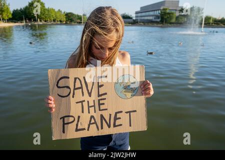 Adolescente tenant une affiche en carton avec l'inscription Save the Planet située près de la rivière dans la rue le jour d'été dans la zone côtière Banque D'Images