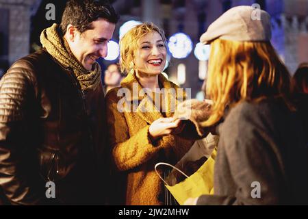 Amis d'âge moyen parlant sans souci tenant des sacs de shopping dans les rues du centre-ville - illuminations de Noël en arrière-plan - heureux amis havi Banque D'Images