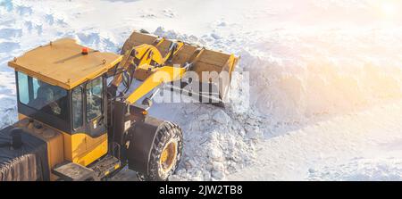 Un gros tracteur orange élimine la neige de la route et dégage le trottoir. Nettoyage et déneigement des routes de la ville en hiver. Déneigement a Banque D'Images