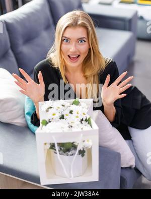 Heureuse femme excitée est agréablement surpris par le bouquet de fleurs qui lui est livré. Belle femme blonde s'exclame avec une expressio heureuse et surprise Banque D'Images