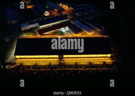 Ferme maison de vache vue aérienne de nuit de drone brillant, abri de vache vue aérienne, lumière brillante à travers le toit lumineux dans la nuit sombre, République tchèque, Europe Banque D'Images