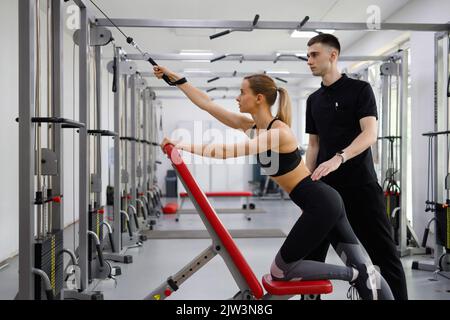 Jeune femme de fitness s'entraîner avec un entraîneur personnel homme dans la salle de gym Banque D'Images