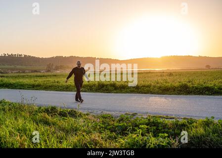 Homme athlète senior marchant sur fond de coucher de soleil. Banque D'Images