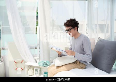 Un jeune homme vietnamien en lunettes lisant un livre Banque D'Images