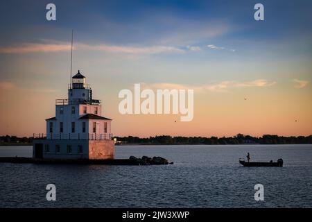 Un pêcheur dans son bateau jette sa ligne près du phare du lac Michigan à Manitowoc, Wisconsin. Banque D'Images