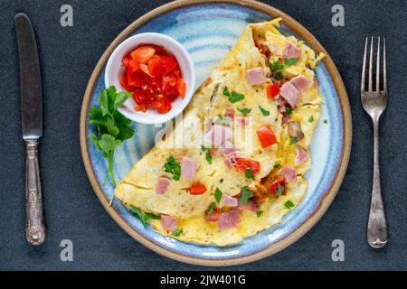 Omelette aux œufs avec jambon, champignons et tomates Banque D'Images