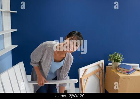 Jeune femme asiatique attrayante emballage ses affaires et souriant à la caméra heureux tout en déplaçant de l'appartement Banque D'Images