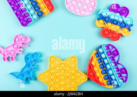 Jeu de jouets colorés populaires de violon le pop sur fond bleu. Nouveaux jouets sensoriels antistress pour les enfants et les adultes. Jouets à bulles tendance. Pose à plat. Banque D'Images