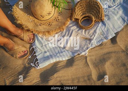 Vue de dessus des accessoires de plage. Chapeau de paille, sac, tongs sur sable à la plage. Banque D'Images