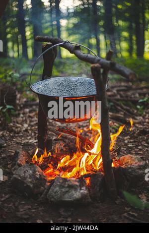 Un cliché vertical de faire une soupe dans la forêt avec un bol en acier sur le feu près de Csesznek, Hongrie Banque D'Images