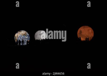 Silhouettes de personnes devant des modèles illuminés de la Terre, de Mars et de la Lune Banque D'Images