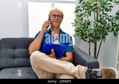 Jeune homme caucasien faisant psychothérapie parlant sur le smartphone à la clinique de psychologie Banque D'Images