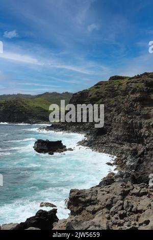 Des falaises rocheuses, certaines avec de la végétation, d'autres dénudées et austères, rencontrent l'océan Pacifique sur la côte de Maui, Hawaii, États-Unis Banque D'Images