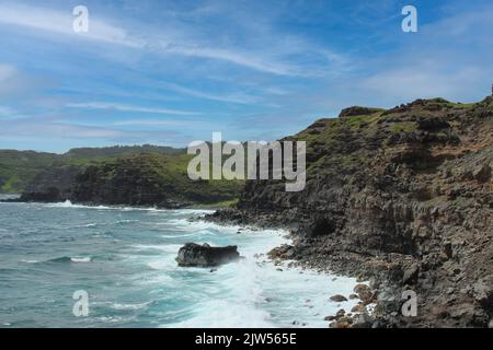 Des falaises rocheuses, certaines avec de la végétation, d'autres dénudées et austères, rencontrent l'océan Pacifique sur la côte de Maui, Hawaii, États-Unis Banque D'Images