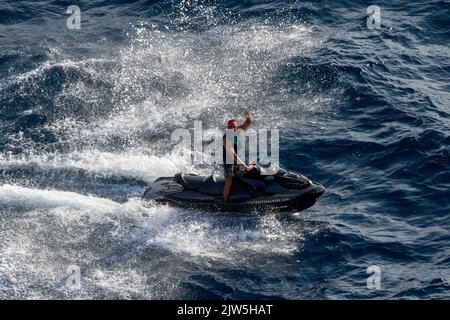 Un jeune homme qui fait du scooter des mers dans la mer Méditerranée à Ibiza en Espagne Banque D'Images