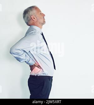 Les effets après du stress de travail. Photo en studio d'un homme mûr souffrant de mal de dos sur fond blanc. Banque D'Images