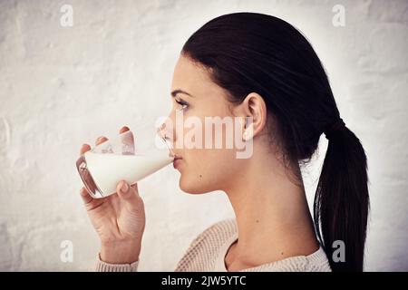 Elle aime son lait. Photo de profil d'une jeune femme qui boit un verre de lait. Banque D'Images